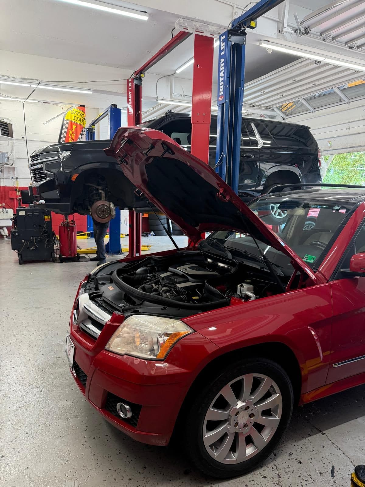 An SUV raised on the lift with a wheel removed for inspection, beside an official Virginia state inspection station banner